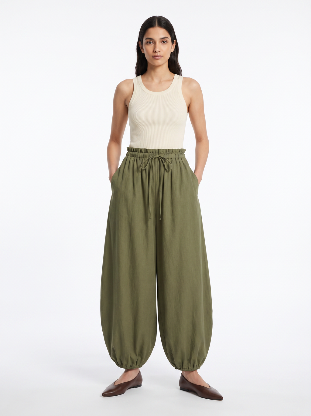 Olive green high waisted balloon pants with gathered waist worn by model on white