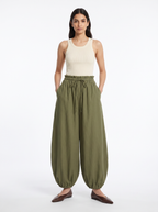 Olive green high waisted balloon pants with gathered waist worn by model on white
