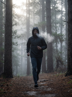 Man wearing black anorak on misty morning forest trail, lifestyle
