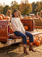 Woman wearing western boots on truck tailgate at pumpkin patch, lifestyle