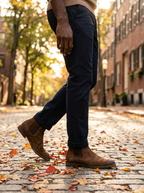 Brown suede Chelsea boots with navy chinos on an autumn cobblestone sidewalk