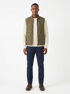 Olive quilted zip-up vest worn by model, front view on white