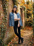 Woman wearing distressed denim jacket against an autumn brick wall